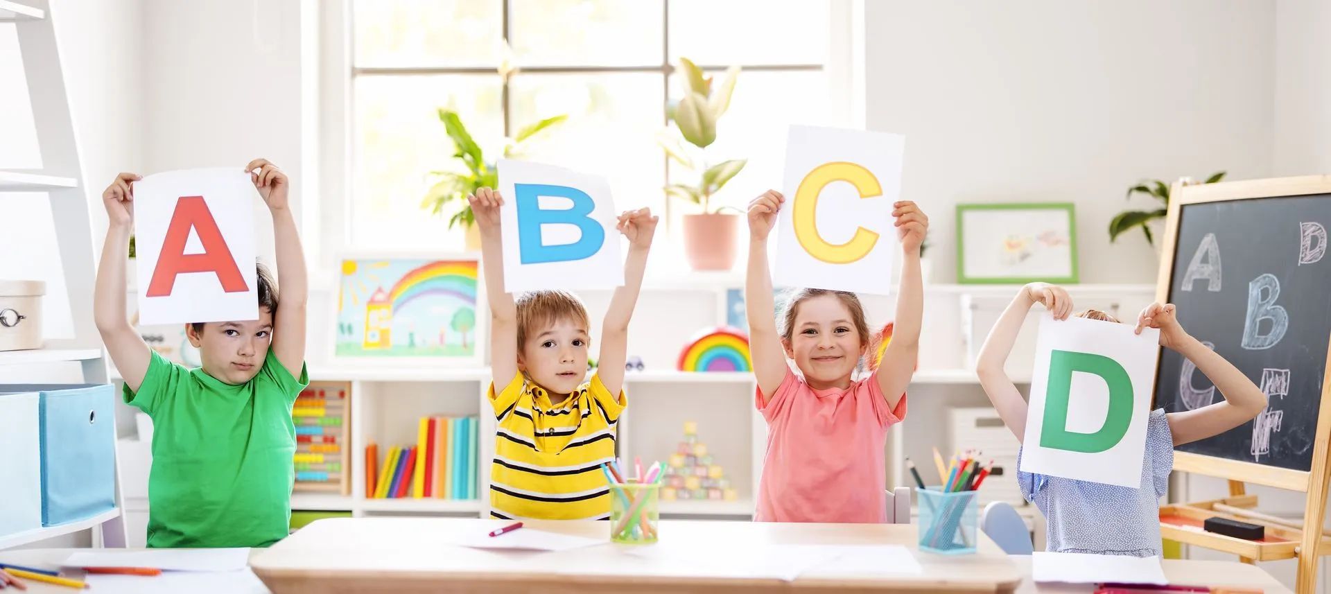 Des enfants tiennent des pancartes colorées de l'alphabet dans une salle de classe