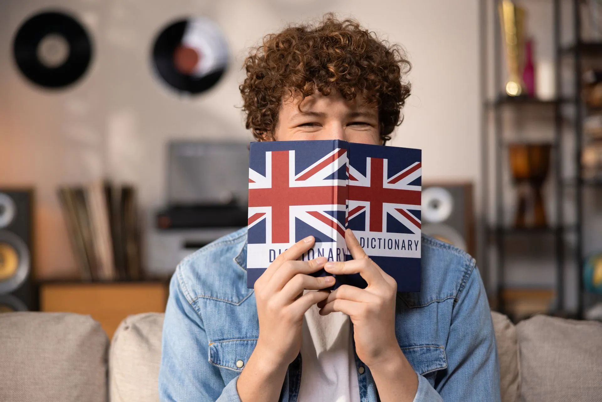 Jeune homme sourient derrière un dictionnaire anglais-français
