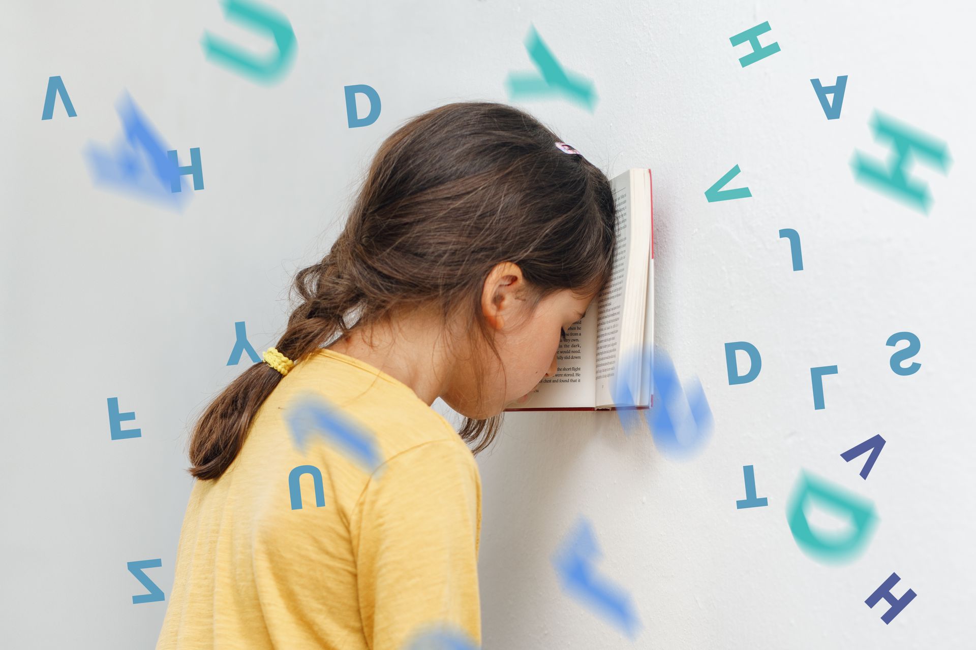 Une petite fille en chemise jaune, la tête appuyée contre un mur, entourée de lettres bleues flottantes