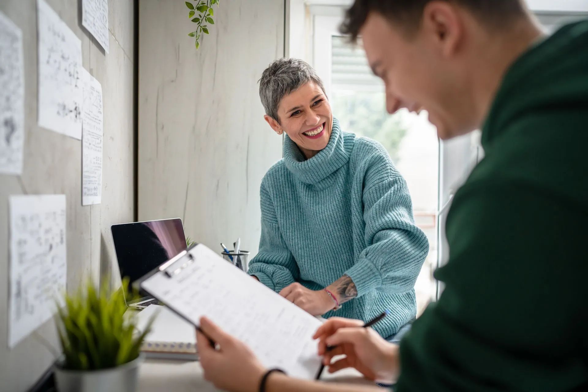 Deux collègues discutent à un bureau, l'un d'eux souriant dans un bureau lumineux