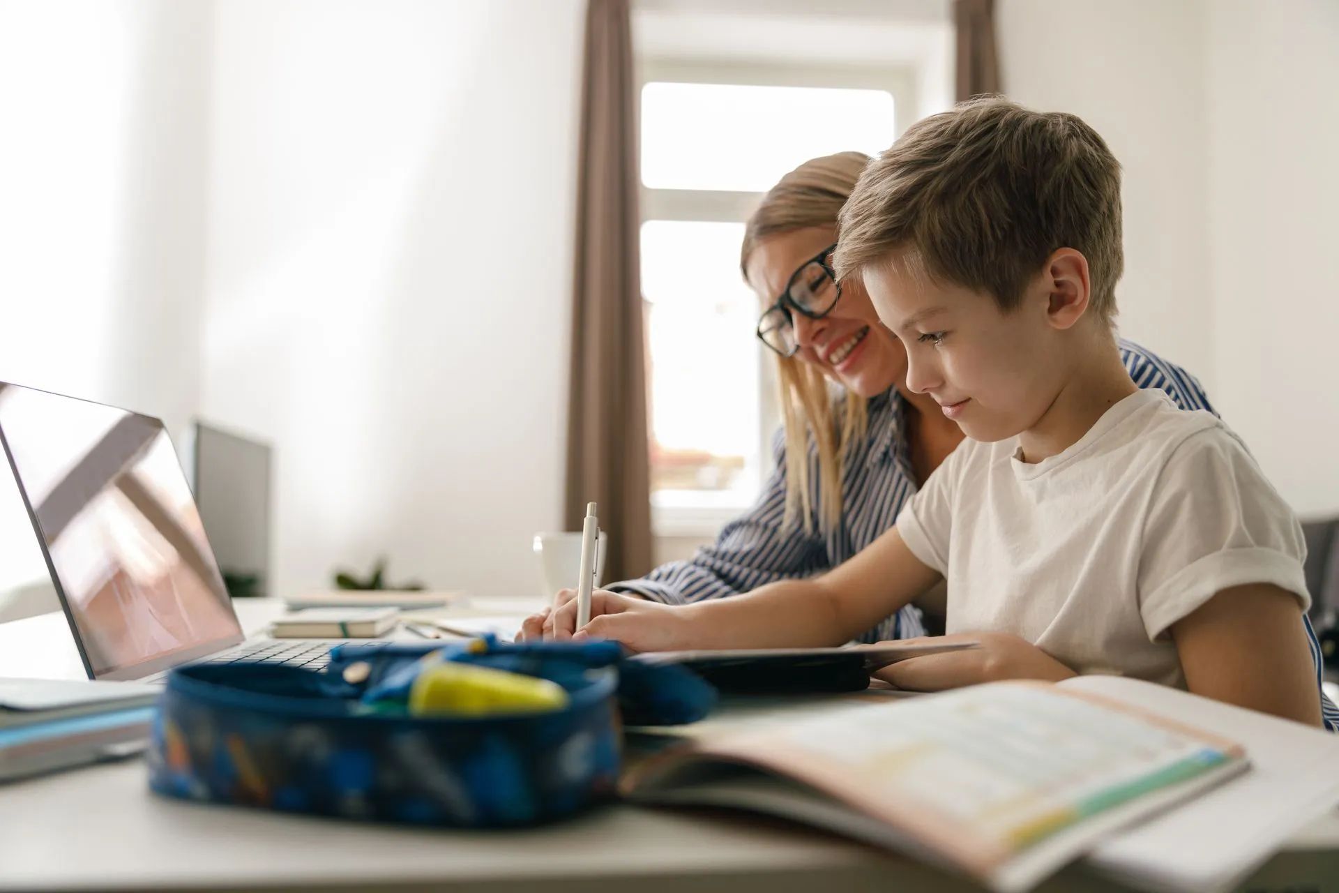 Une femme aide un enfant à faire ses devoirs