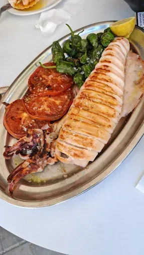 Calamares a la plancha con tomates, pimientos y limón en bandeja de plata.