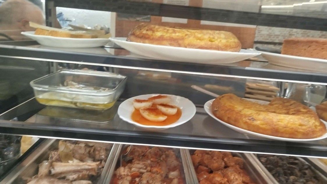 Vitrina de panadería con una variedad de pasteles, postres y productos horneados salados en estantes de vidrio.