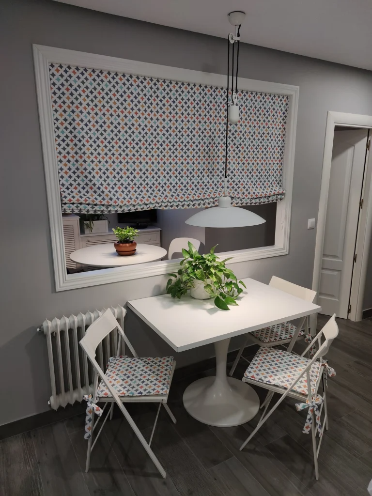 Un comedor con una mesa y sillas frente a una ventana.