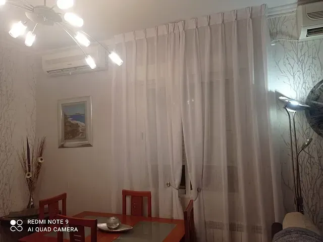 Una sala de estar con mesa y sillas y cortinas blancas.