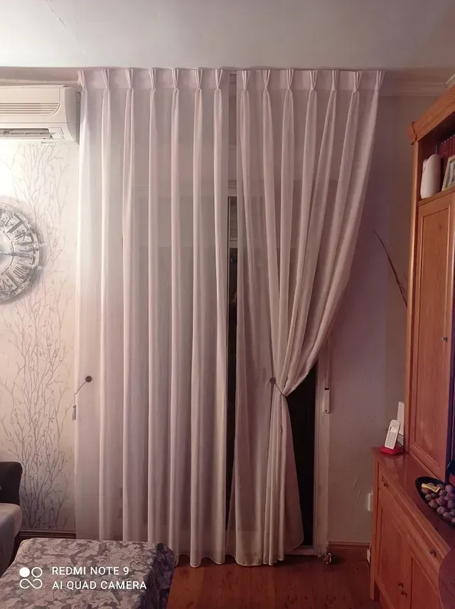 Una sala de estar con cortinas blancas y un reloj en la pared.