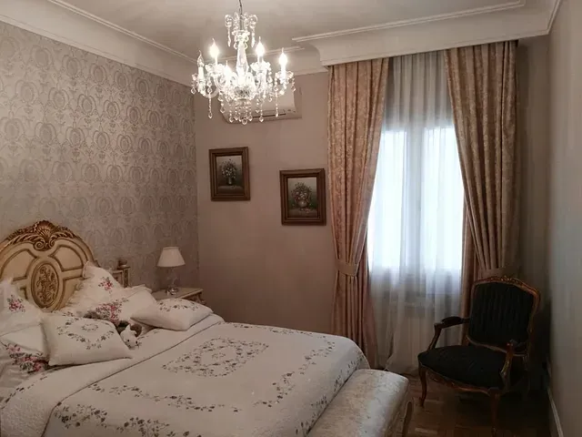 Un dormitorio con una cama, una silla y una lámpara de araña.