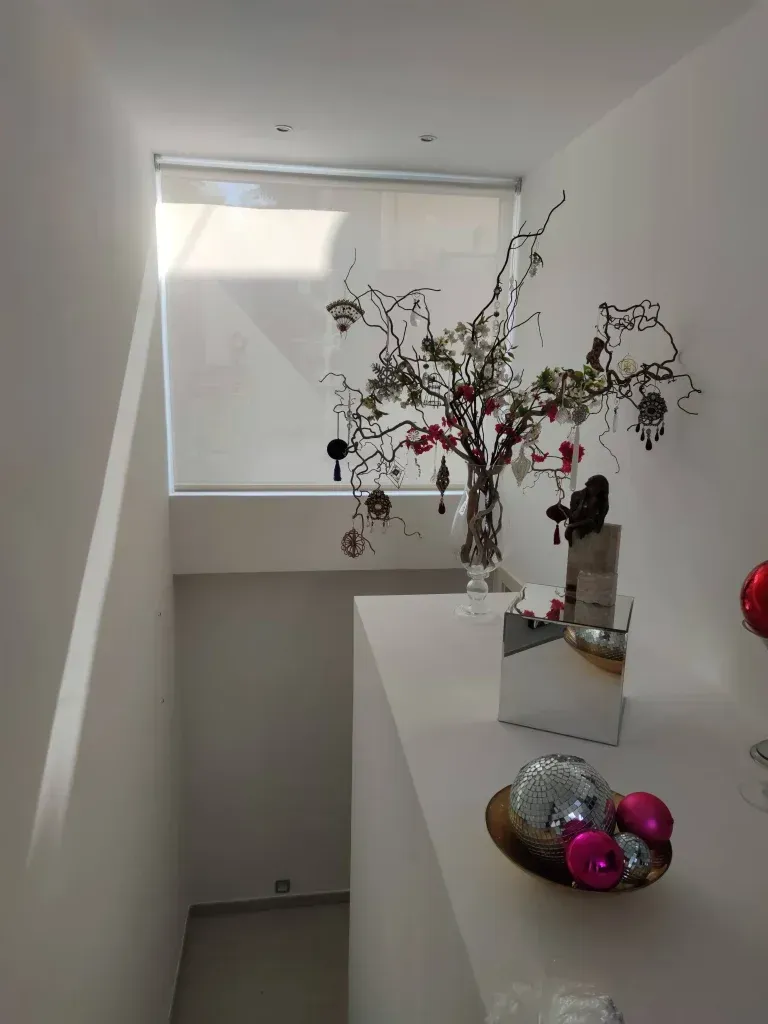 Una escalera con un jarrón de flores y un cuenco con adornos navideños.