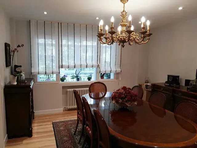 Un comedor con una mesa larga y sillas y una lámpara de araña.