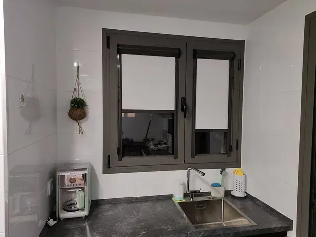 Una cocina con fregadero y una ventana con persianas.