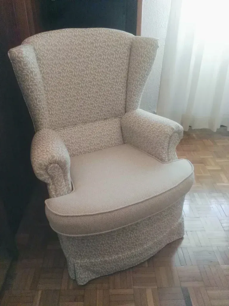 Una silla blanca está colocada sobre un piso de madera en una habitación.