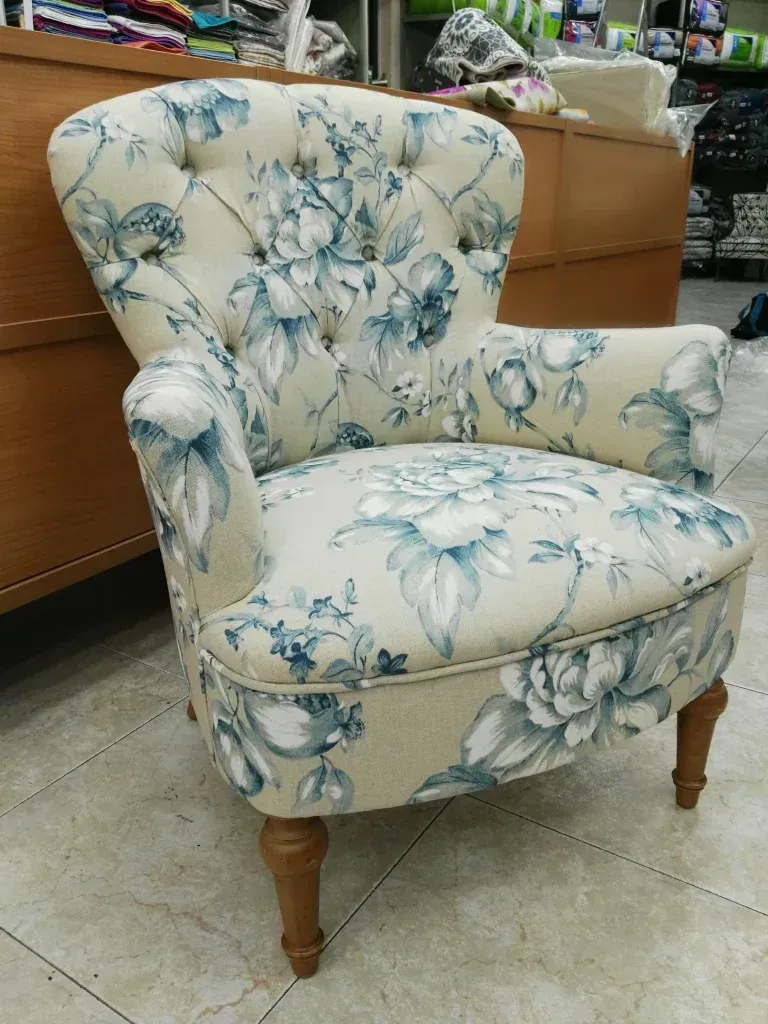 Una silla con un estampado floral está colocada sobre un suelo de baldosas.