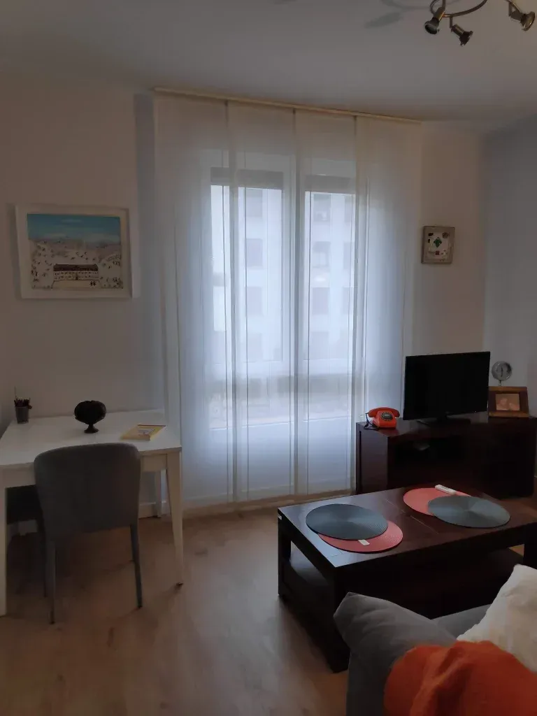 Una sala de estar con un sofá, una mesa, sillas y un televisor.