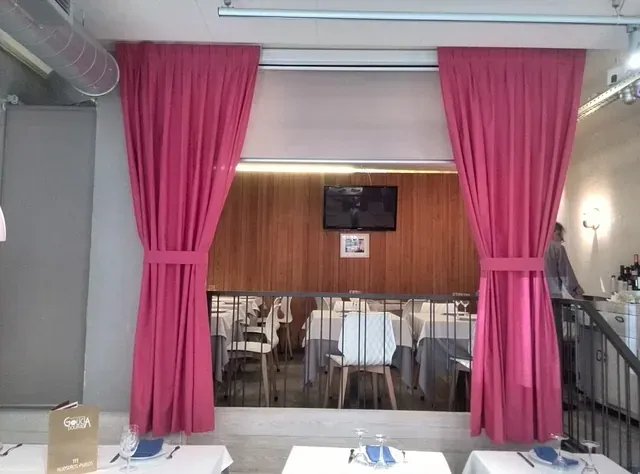 Un restaurante con cortinas rosas y mesas y sillas.