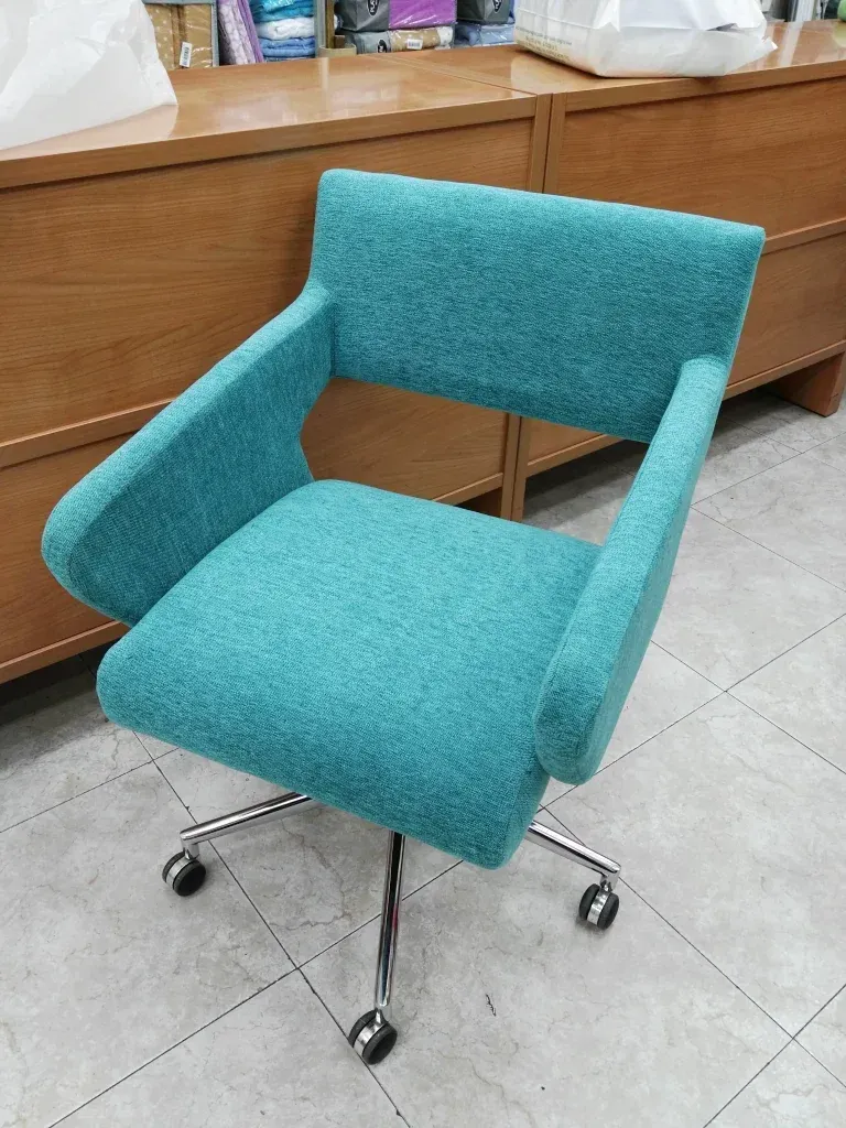 Una silla azul con ruedas está colocada sobre un suelo de baldosas delante de un mostrador de madera.