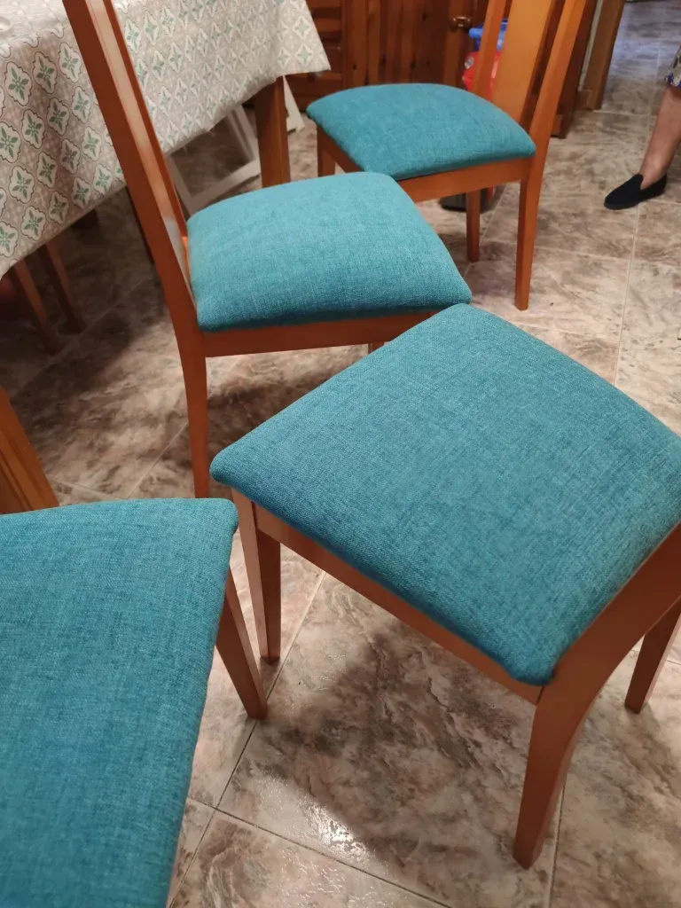 Un grupo de sillas con cojines azules están sentadas una al lado de la otra en una habitación.