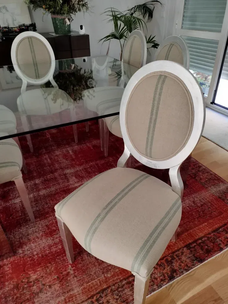 Un comedor con una mesa de cristal y sillas sobre una alfombra.