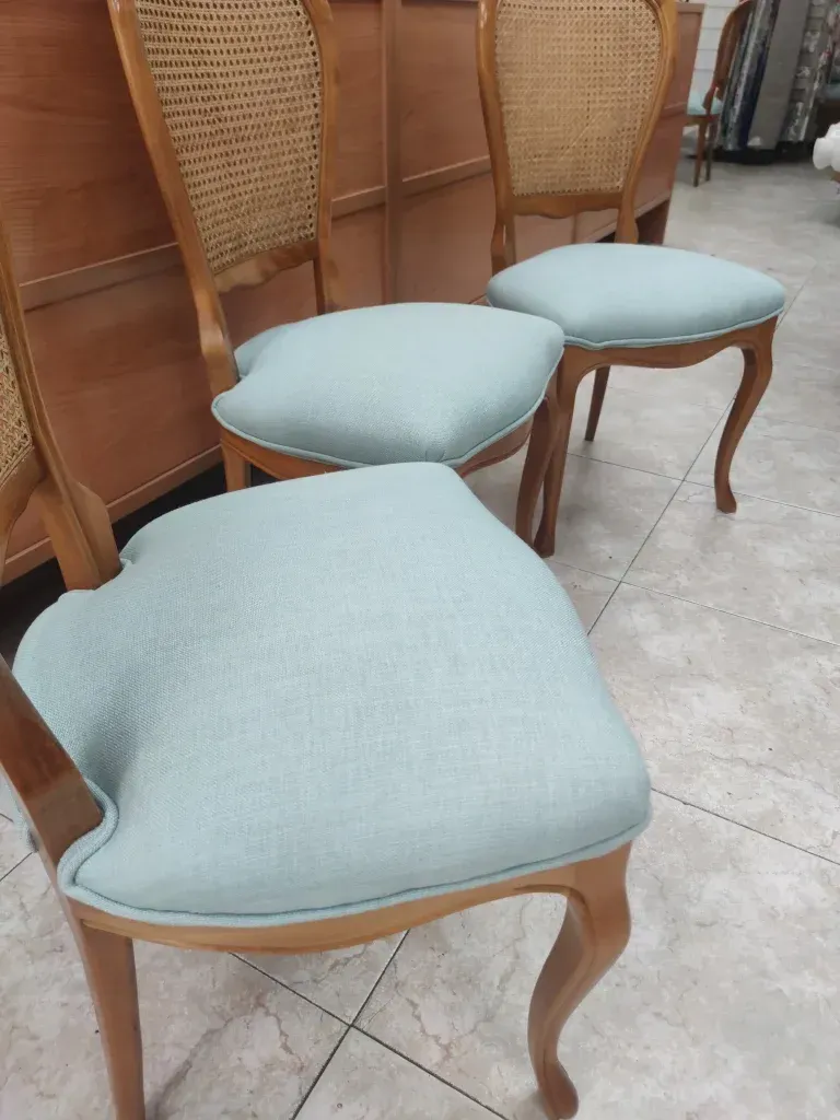 Tres sillas están sentadas una al lado de la otra sobre un piso de baldosas.