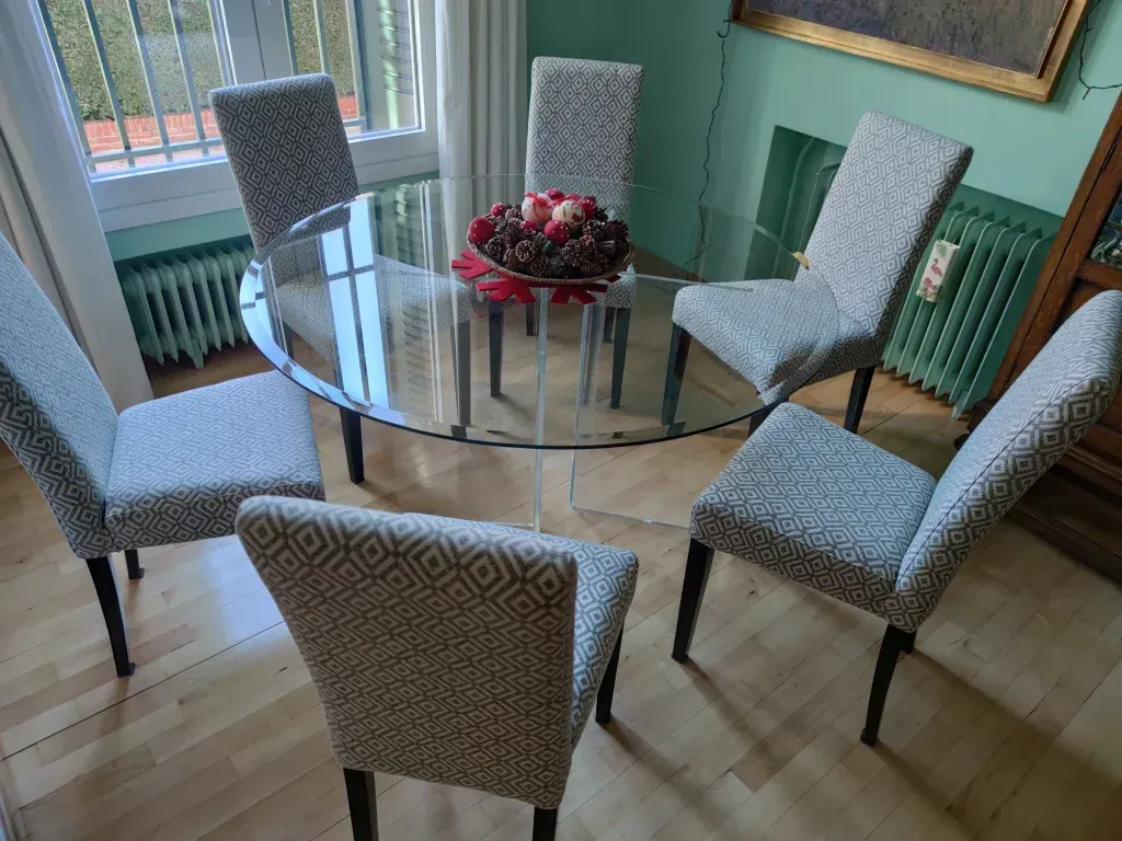 Un comedor con una mesa de cristal y sillas.
