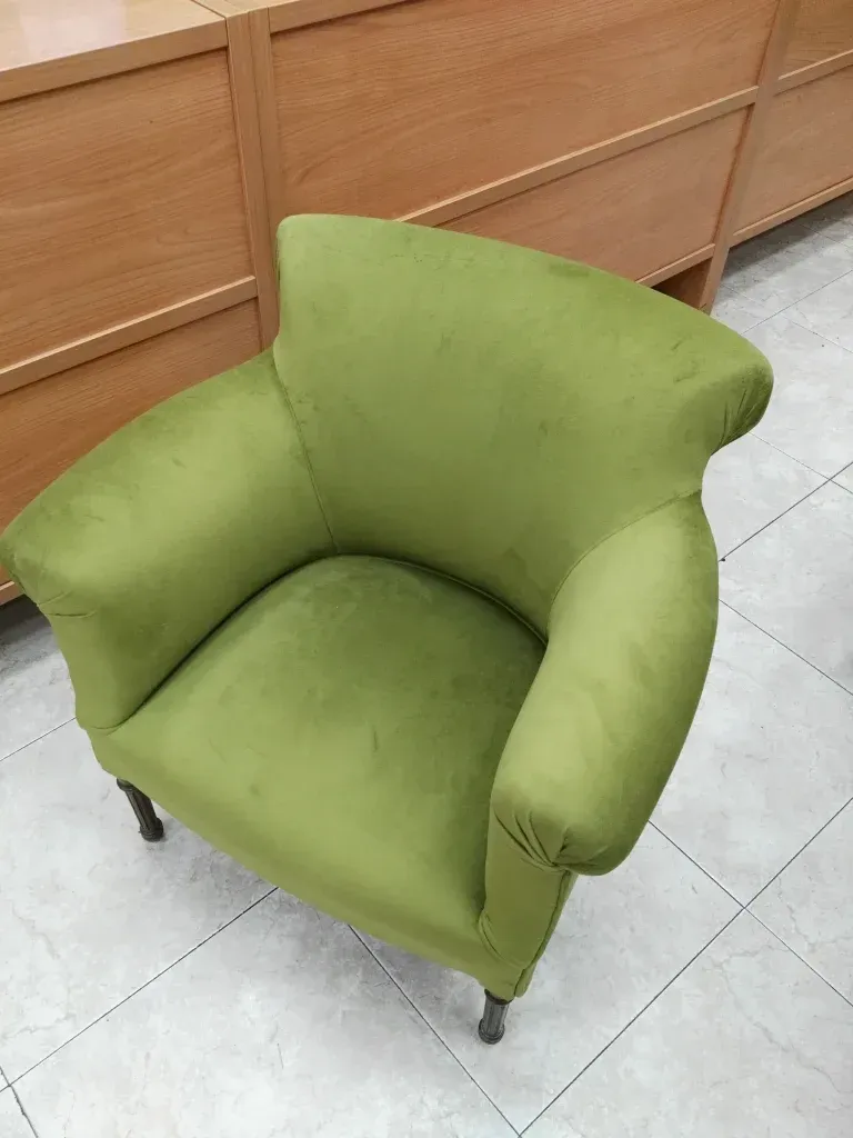 Una silla verde está colocada sobre un suelo de baldosas en una habitación.