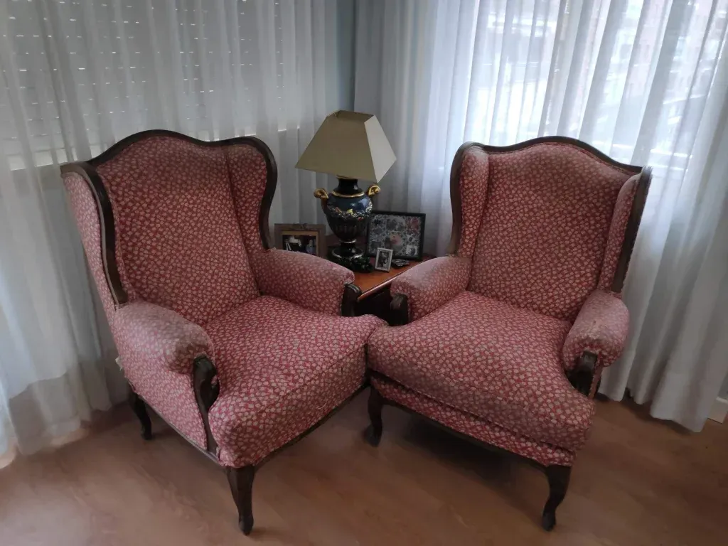 Dos sillas rosas están una al lado de la otra en una sala de estar.