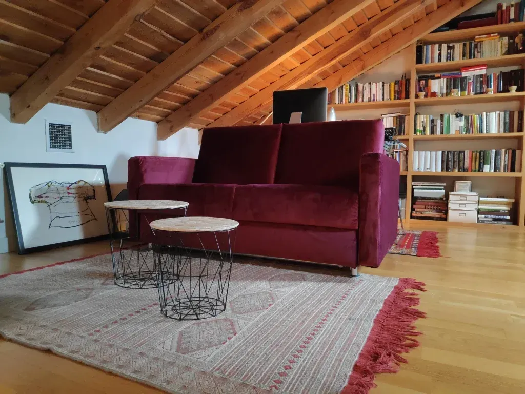 Una sala de estar con un sofá morado y dos mesas.