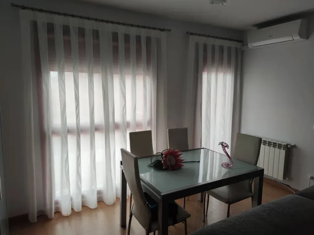 Un comedor con una mesa y sillas frente a una ventana.