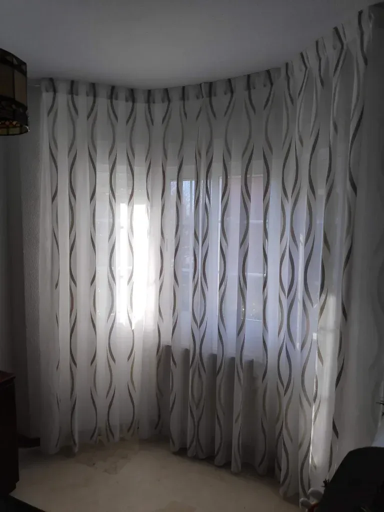 Una sala de estar con una gran ventana y cortinas.