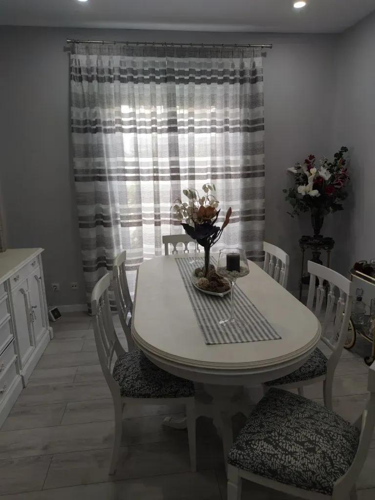 Un comedor con una mesa y sillas y un jarrón con flores sobre la mesa.