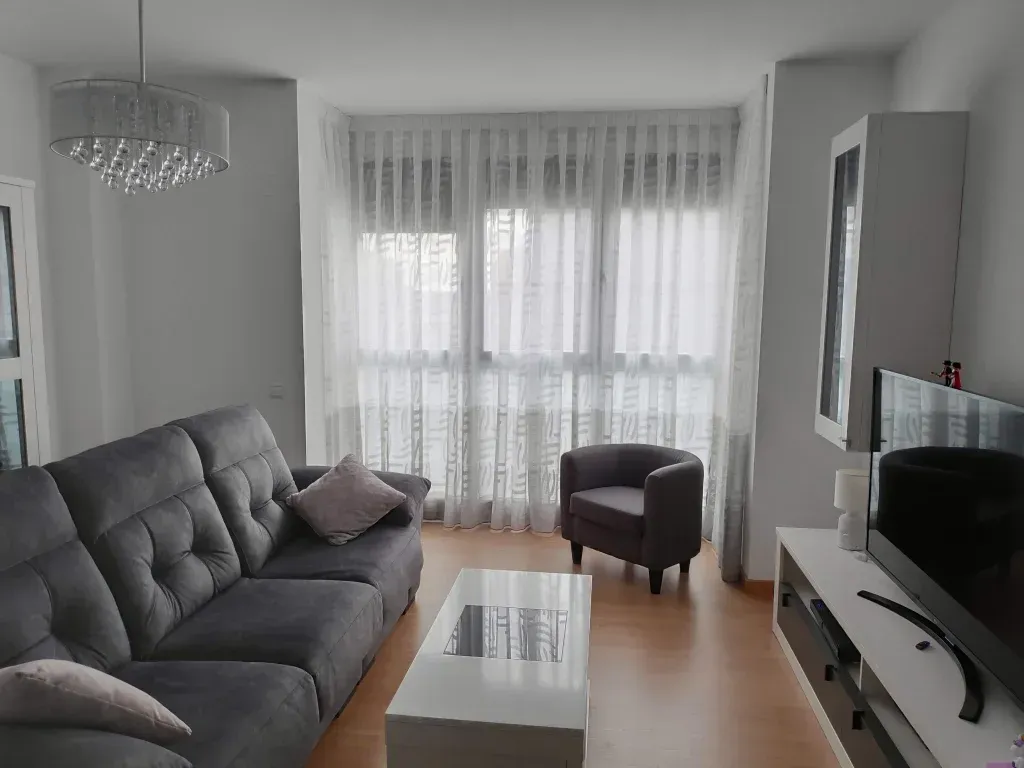 Una sala de estar con un sofá, un sillón y un televisor.