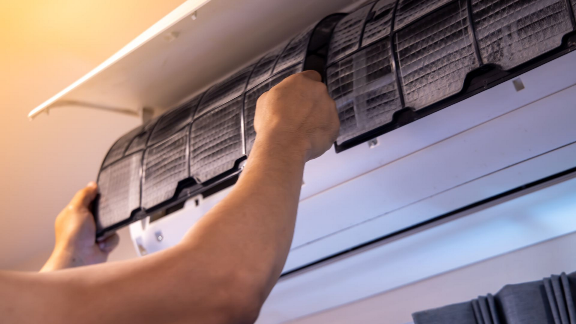 Personne nettoyant un filtre de climatiseur.