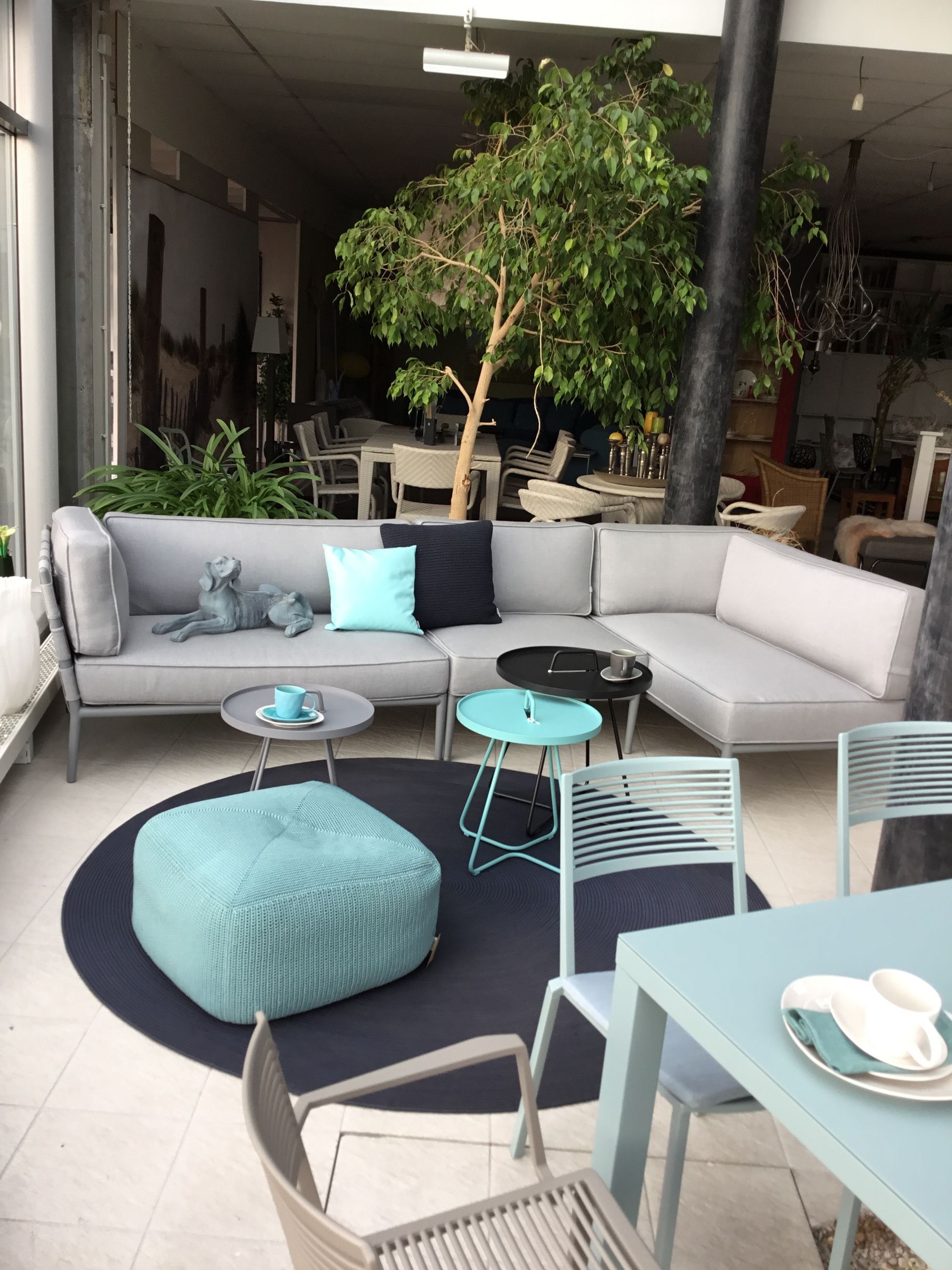 Gartenlounge bestehend aus einer Sitzbank über Eck mit Sitzpolstern und Kissen, sowie Beistelltischen und einem Hocker