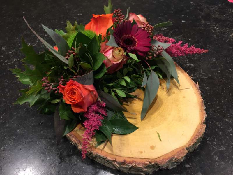 Bloemstuk rode bloemen boomstronk