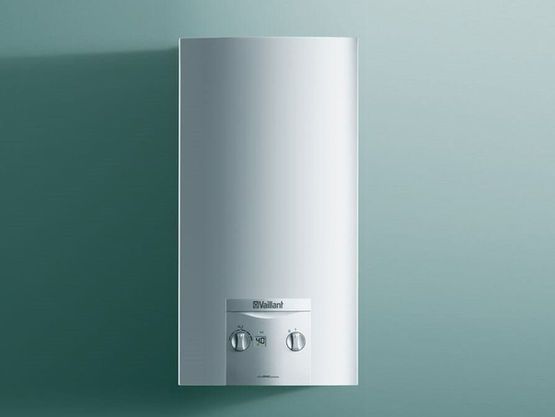 Aquecedor de água branco de parede com dois botões de controle em uma parede azul-petróleo.