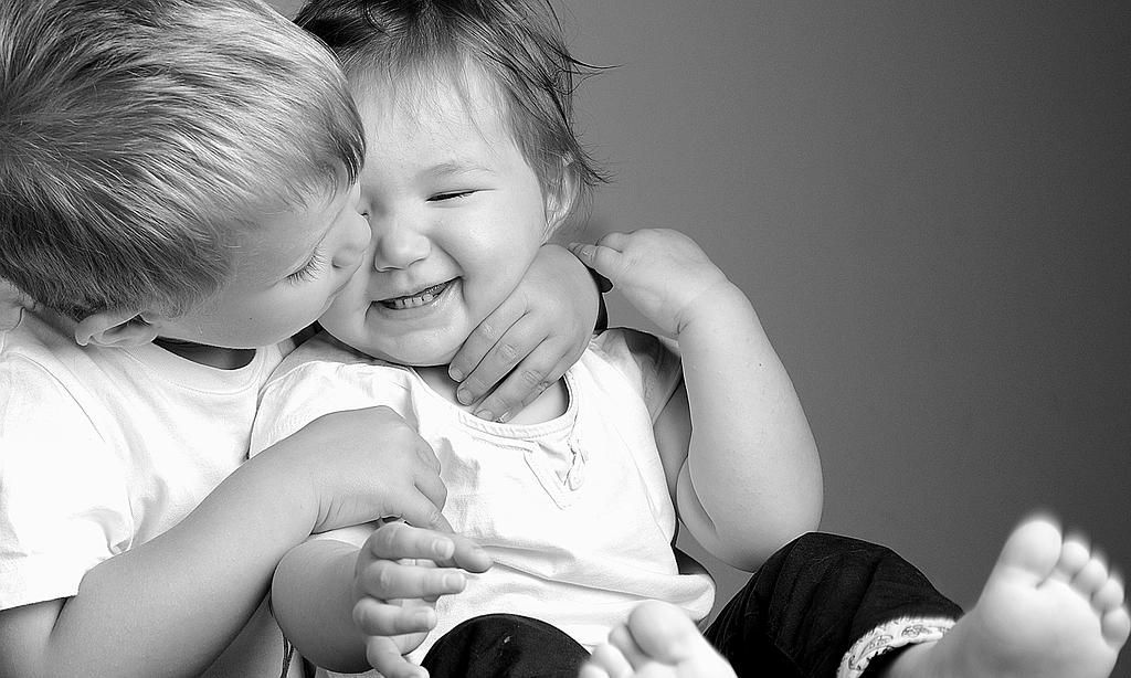 Deux enfants qui rient et s'enlacent étroitement.