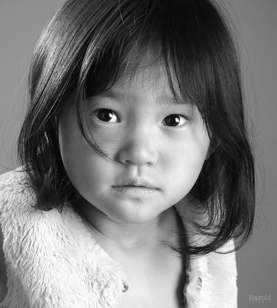 Portrait en noir et blanc d'un jeune enfant aux cheveux mi-longs, regardant directement l'objectif.