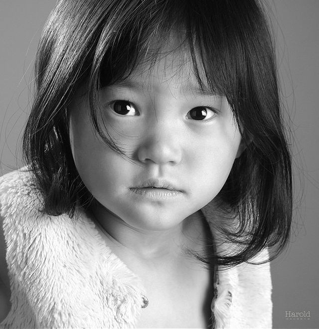 Portrait en noir et blanc d'un enfant aux cheveux mi-longs, regardant l'objectif avec une expression sérieuse.