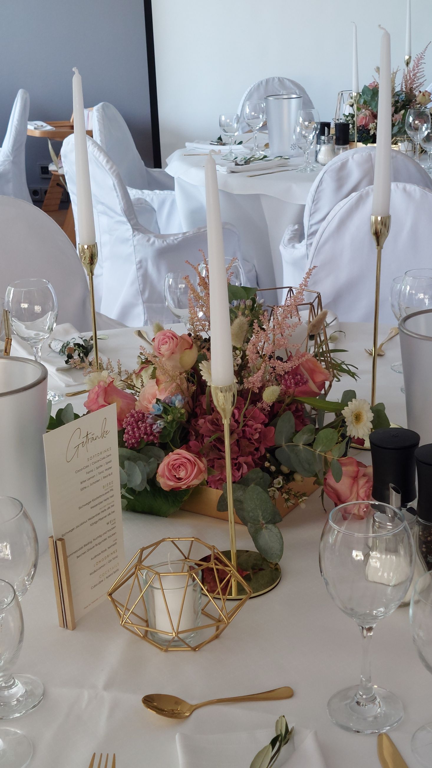 Hochzeitsdekoration mit rosa Blumen und goldenen Kerzenhaltern auf festlicher Tafel
