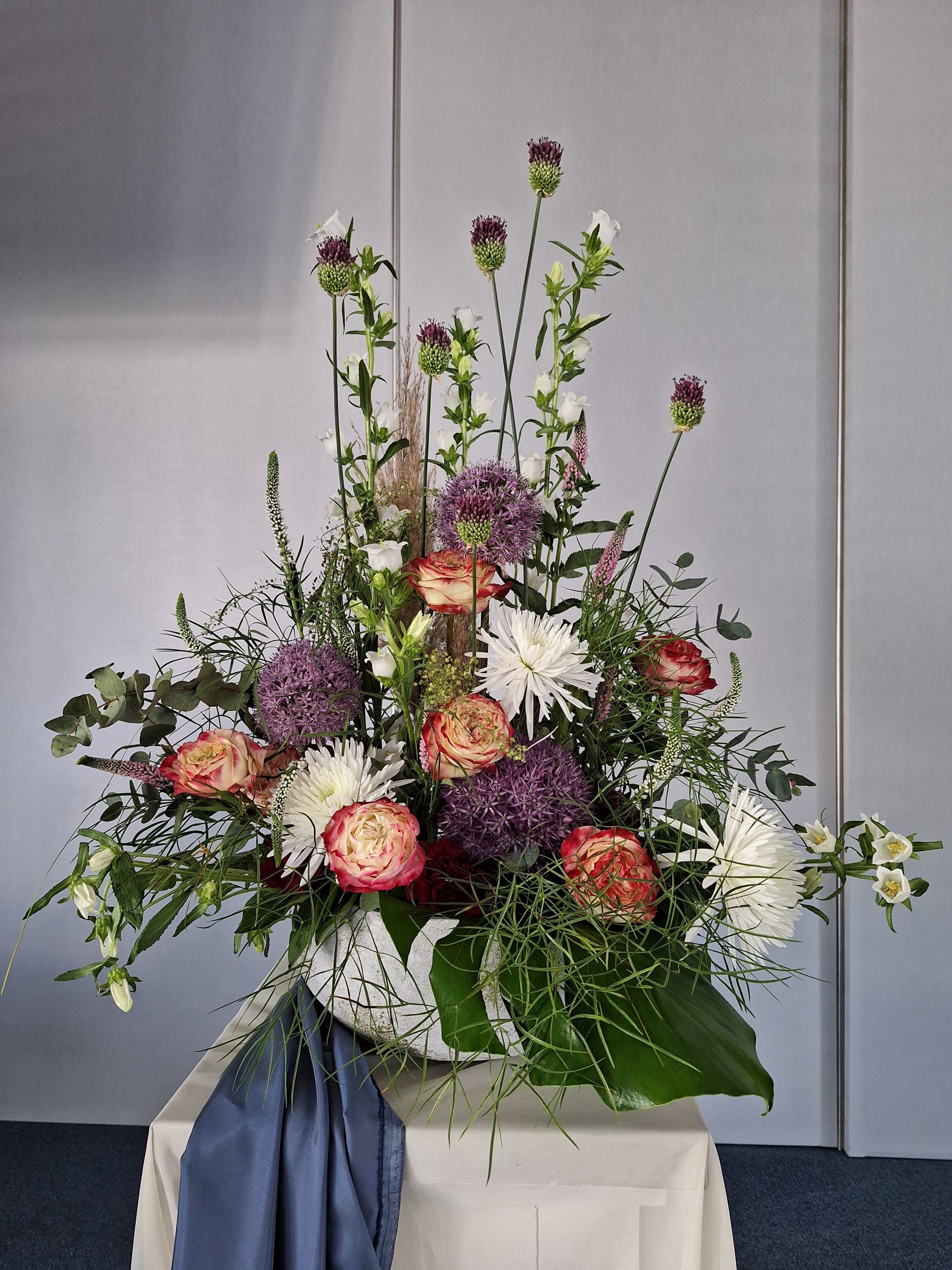 Lockeres Blumenarrangement mit Wildblumen und natürlichen Grünpflanzen