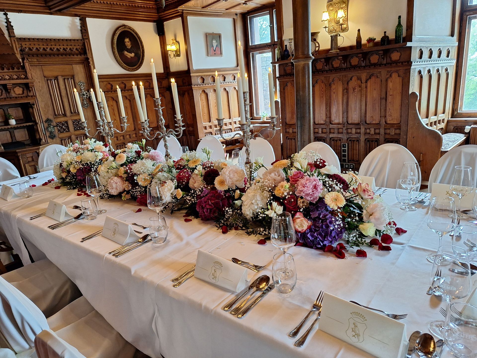 Hochzeitstafel mit üppiger Blumendekoration in historischem Festsaal