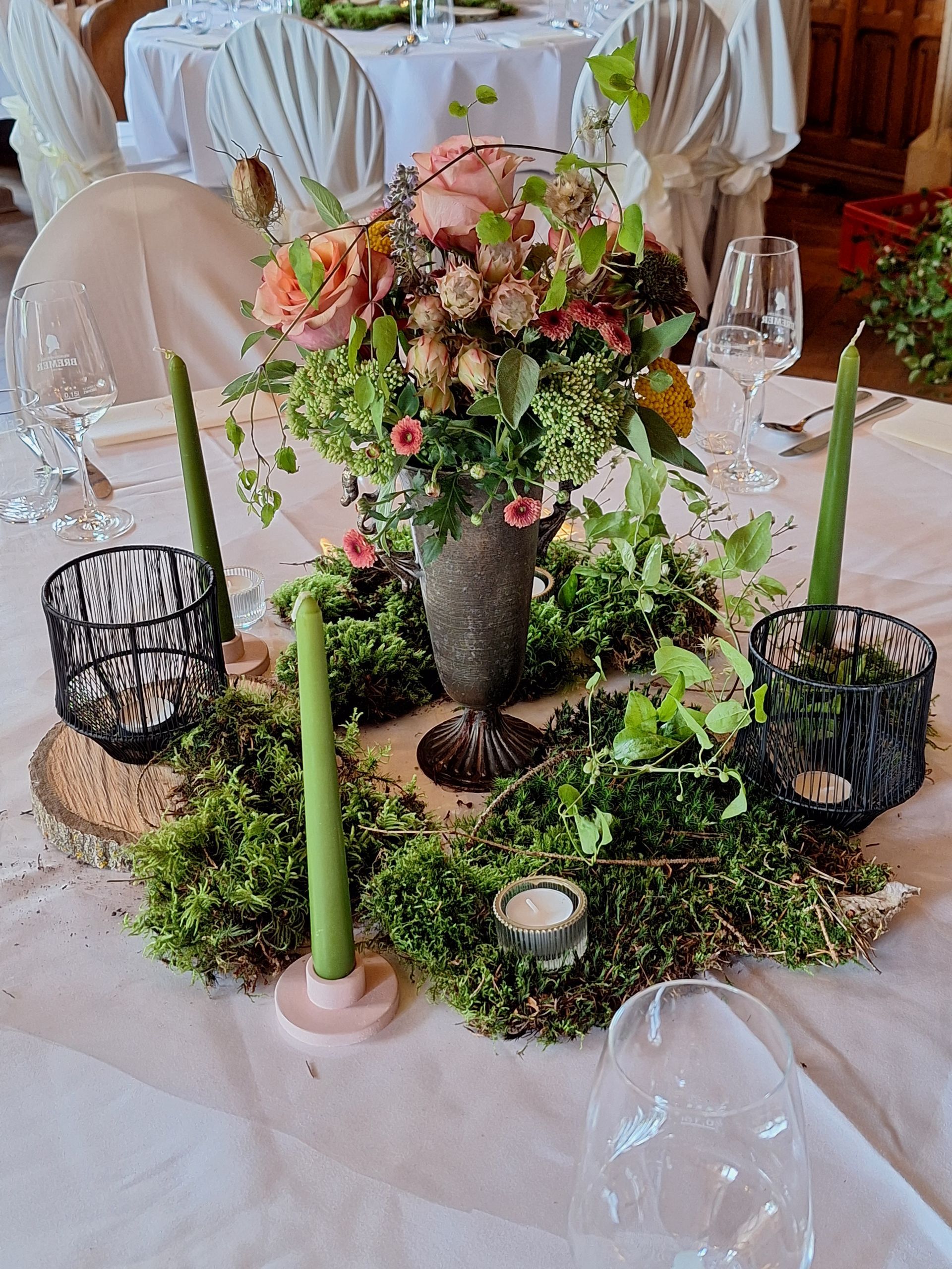 Florales Tischgesteck mit rosa Blüten und Moosdeko im natürlichen Stil