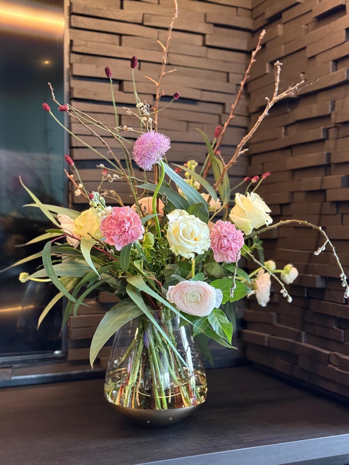 Florale Tischdekoration mit rosa Blüten und Zweigen im modernen Stil