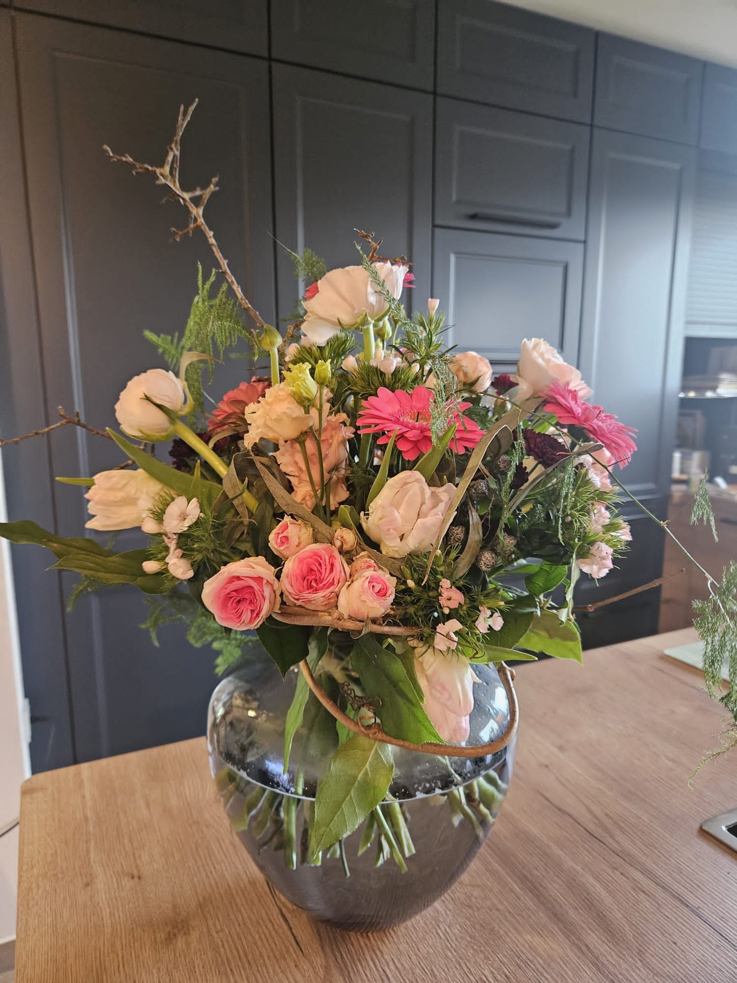 Farbenfroher Blumenstrauß mit rosa Rosen und saisonalen Blüten im Glasgefäß