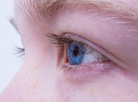 Eine Nahaufnahme des blauen Auges einer Person mit langen Wimpern.