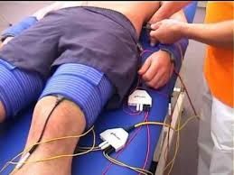 Ein Mann liegt auf einem Bett, an seinen Beinen sind Drähte befestigt.