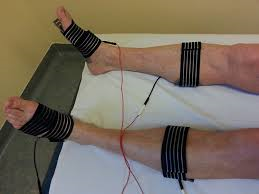 Eine Person liegt mit Elektroden an den Beinen auf einem Bett.