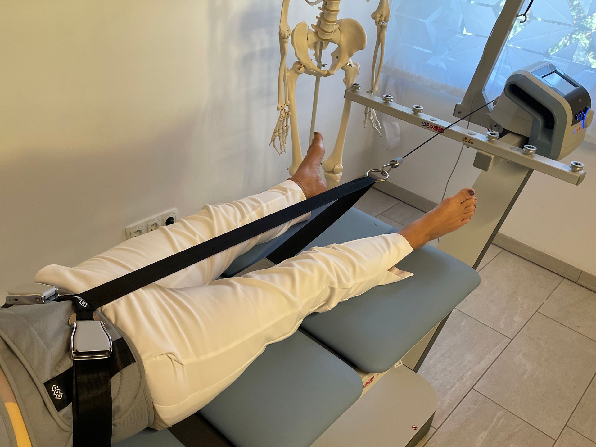 Eine Person liegt auf einem Tisch, im Hintergrund ist ein Skelett zu sehen.