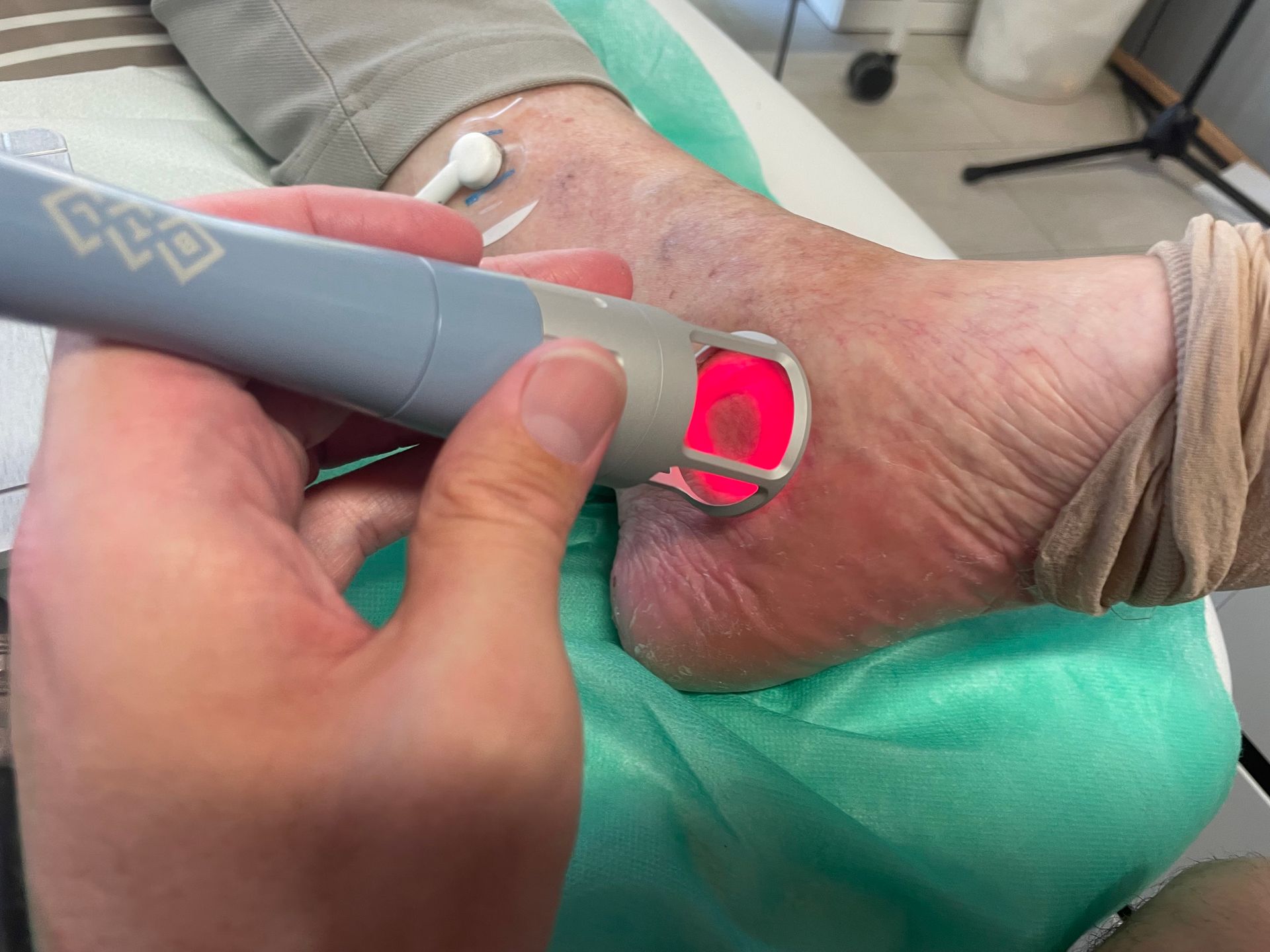 Eine Person hält ein Gerät über den Fuß einer anderen Person.