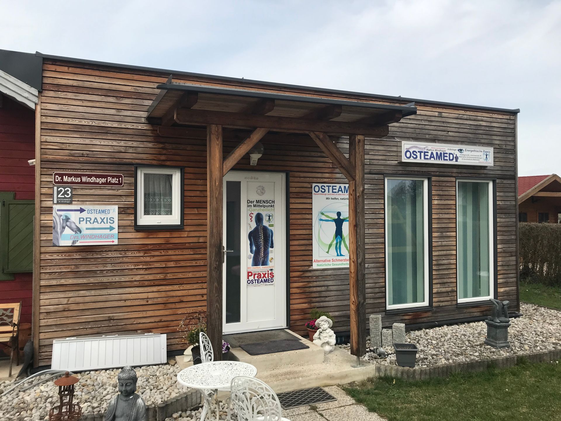 Ein kleines Holzhaus mit einer Veranda und einer Statue davor.