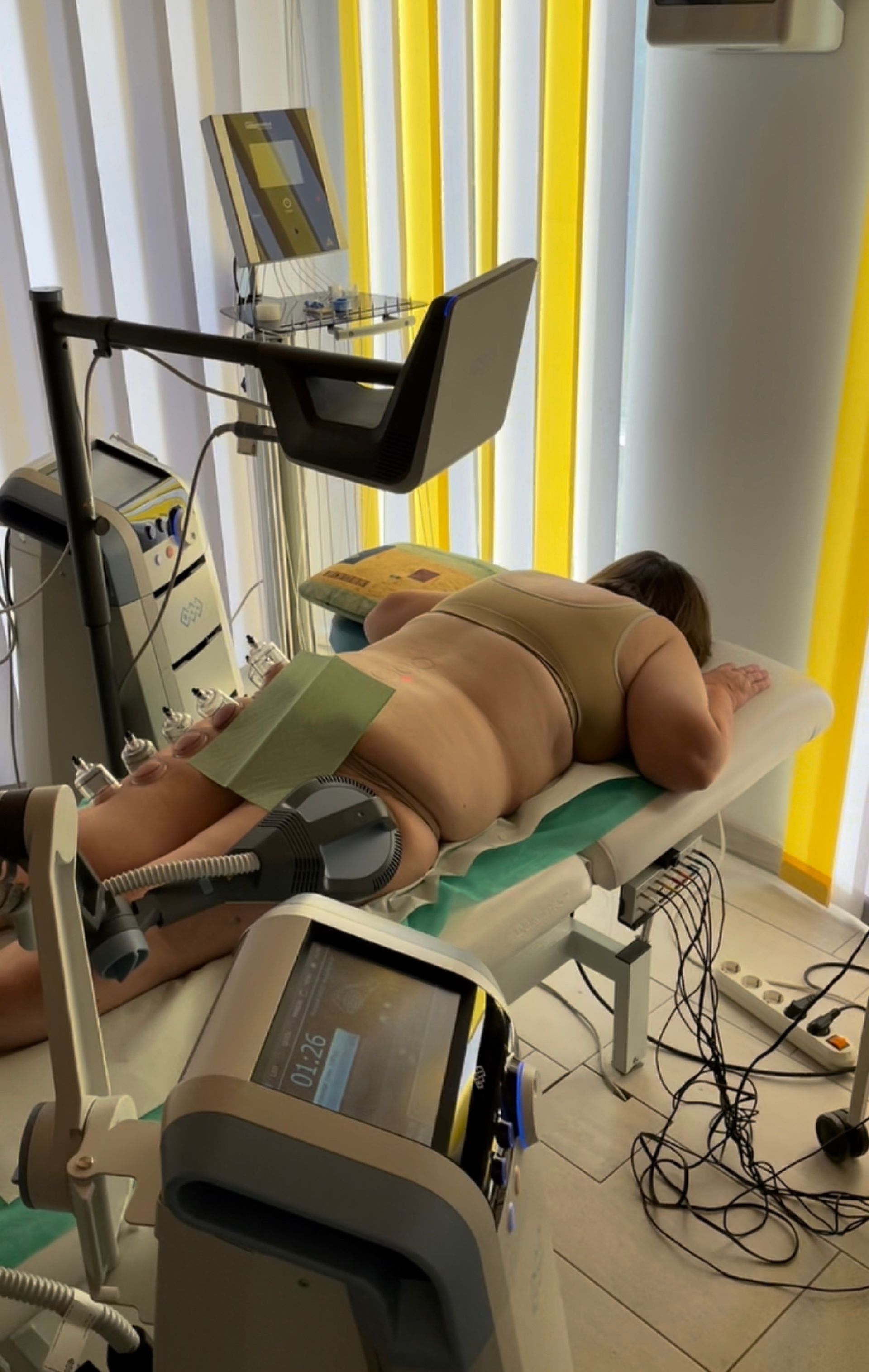 Eine Frau liegt mit einer Maschine auf ihrem Rücken auf einem Bett.